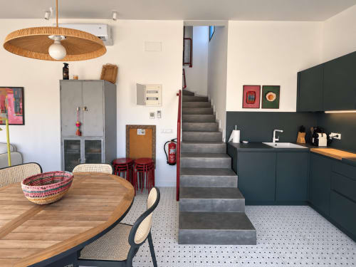 Cocina y comedor de cabaña costera moderna en Baiona con vistas al mar, mueblería oscura, mesa de madera y escaleras