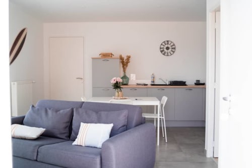 Modern apartment living area with gray sofa, dining table, and kitchenette at Résidence des Sables, Mably
