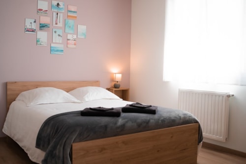Cozy bedroom at Résidence des Sables in Mably with wooden bed, white pillows, and coastal-themed wall art gallery.