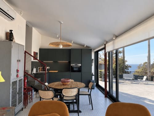 Moderna cocina-comedor de la casita El Román en Baiona, con vistas al mar a través de puertas de cristal y paisaje costero visible