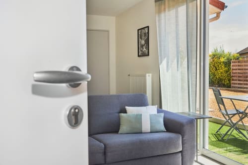 Modern apartment door with blue armchair, garden view at Résidence des Sables, Mably