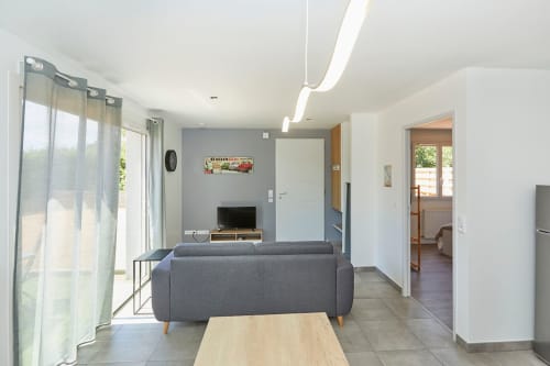 Modern living room in Résidence des Sables apartment with gray sofa, wooden table, and access to bedroom and kitchen areas