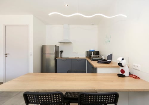 Modern kitchen-dining area at Résidence des Sables, Mably with wooden table, dark cabinetry, stainless steel appliances and