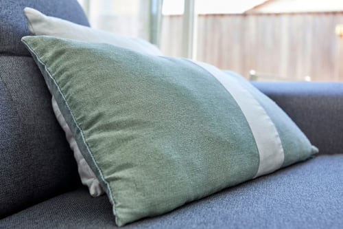 Decorative green and white striped pillows arranged on blue sofa at Résidence des Sables apartment in Mably