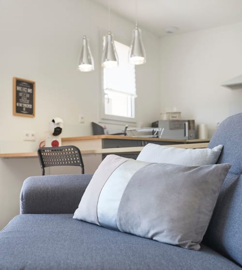 Modern Paris apartment lounge at Résidence des Sables with blue sofa, pillows, pendant lights, and desk view