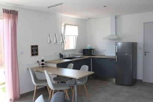 Modern kitchen and dining area in Appartement 3 at Résidence des Sables, Mably with black cabinetry and wooden table.