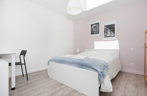 Modern bedroom at Résidence des Sables, Mably with white bed, pink walls, desk and black chair