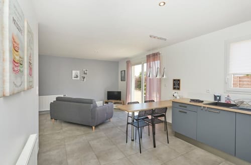Modern open-plan apartment at Résidence des Sables in Mably with gray sofa, dining table, and kitchen area