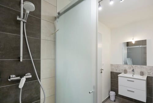 Modern bathroom in Résidence des Sables apartment with walk-in shower, sink vanity, and heated towel rail