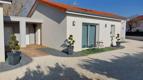 Modern apartment exterior at Résidence des Sables in Mably with terrace, potted plants, and courtyard seating area