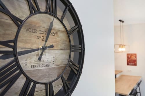 Vintage railway clock on wall at Résidence des Sables apartment in Mably, with interior hallway visible