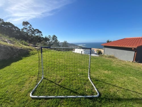 Red de fútbol portátil en jardín verde con vistas al mar, jardín de cabaña en Baiona, España