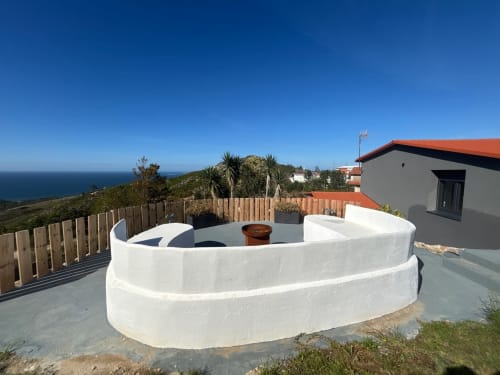 Bañera de hidromasaje blanca redonda con vistas al océano en la terraza de la casa rural El Román en Baiona, España