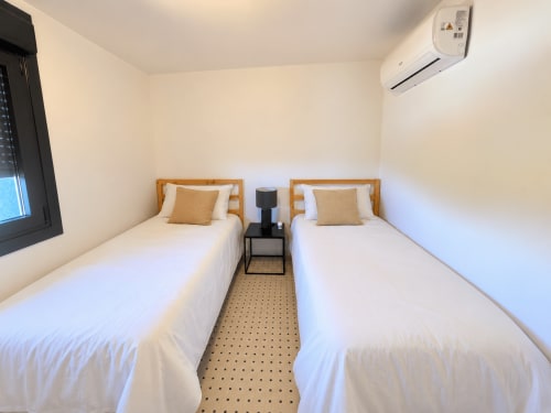 Dormitorio doble con camas de madera y vistas al mar en la casita El Román de Baiona