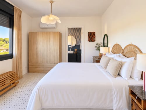 Dormitorio moderno en la casa rural El Román, Baiona con vistas al mar, armario de madera, cabeceros tejidos y ropa de cama blanca