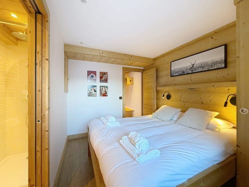 Chambre de chalet moderne à Montgenèvre avec deux lits jumeaux, éclairage chaleureux et vue sur les montagnes de l'appartement Le Chaberton