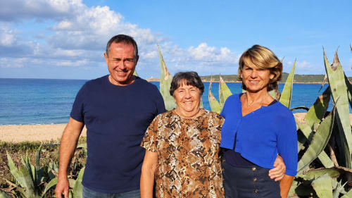 Trois personnes souriantes à l'Hôtel Thalassa à Cargèse, avec plage, agaves et mer Méditerranée en arrière-plan