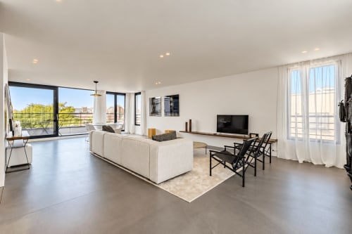 Suite luxe moderne à l'hôtel Livorno à Bruxelles avec canapé crème, chaises noires, TV, sols en béton poli