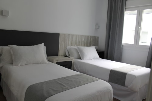 Habitación doble en Hostal El Camionero en Burguillos del Cerro con ropa de cama blanca y decoración moderna