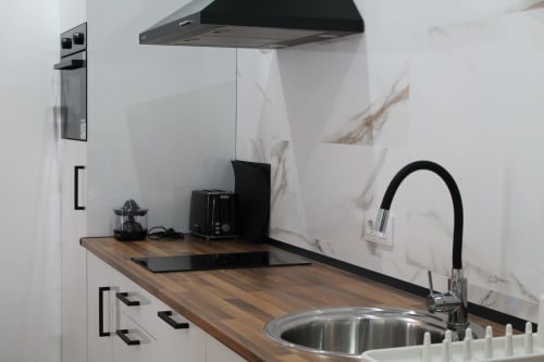 Cocina moderna en Hostal El Camionero con salpicadero de mármol, encimera de madera, fregadero de acero inoxidable y negro
