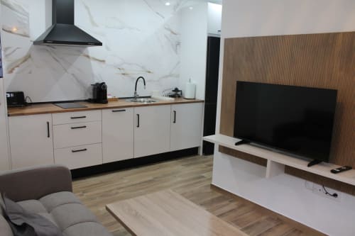 Moderna cocina y sala de estar del Hostal El Camionero en Burguillos del Cerro con acabado de mármol y televisor