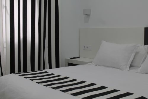 Dormitorio moderno del Hostal El Camionero con cortinas rayadas, ropa de cama blanca y acentos geométricos negros
