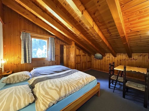 Chambre twin à l'Hôtel les Bouquetins à Zinal avec poutres apparentes, vue montagne et décor rustique alpin