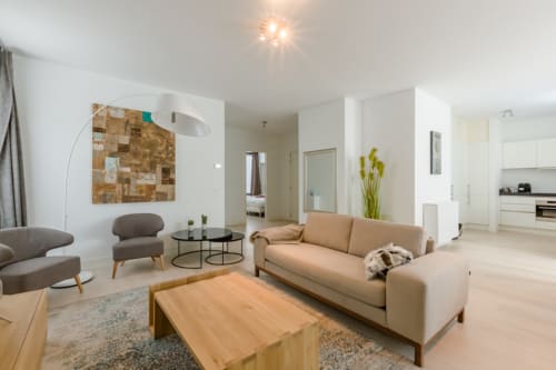 Salon élégant de l'appartement bruxellois avec canapé beige, mobilier contemporain et cuisine ouverte à The Livorno