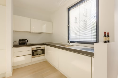 Cuisine moderne dans un élégant appartement bruxellois à The Livorno avec armoires blanches, électroménagers en acier inoxydable et grand