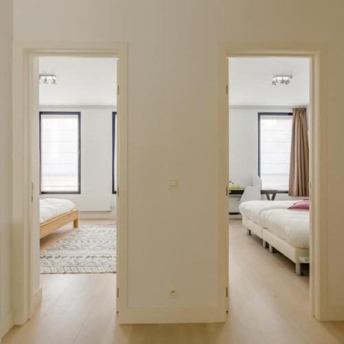 Couloir d'appartement moderne au Livorno Brussels avec portes ouvertes sur chambres jumelles, design minimaliste et fenêtres lumineuses