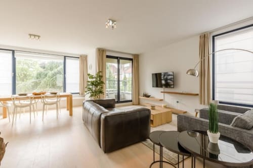 Espace de vie ouvert et moderne à l'hôtel Livorno en Belgique avec salle à manger, coin salon et baies vitrées