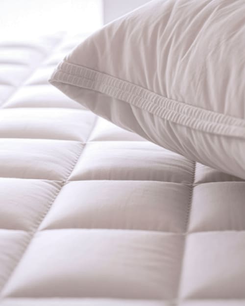 Dettaglio della biancheria da letto trapuntata bianca con cuscino presso il B&B Il Giardino di Ulisse in Italia