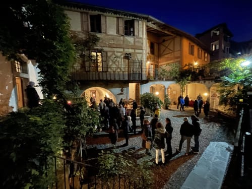 Serata in cortile a Roseto del Drago, Ponte in Valtellina, con ospiti che godono del patio in pietra illuminato e