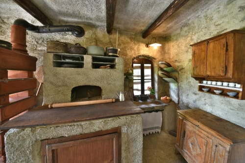 Cucina rustica dell'appartamento La Sorgente a Roseto del Drago, con muri in pietra, travi di legno, camino tradizionale e
