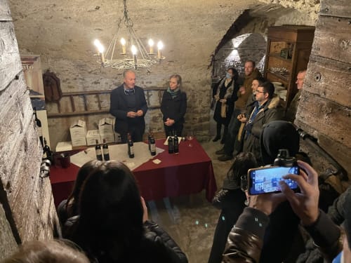 Degustazione di vini nella storica cantina in pietra a Roseto del Drago, Ponte in Valtellina, con ospiti riuniti attorno a tavoli rivestiti di rosso