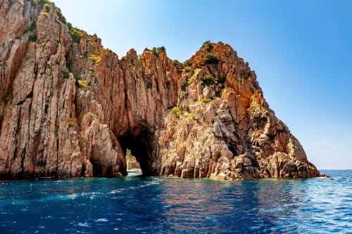 Côte rocheuse dramatique et rouge avec grotte marine près de l'Hôtel Thalassa à Cargèse, Corse