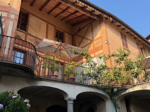 Storico cortile italiano con portico ad archi, travi in legno e terrazza coperta di edera a Roseto del Drago