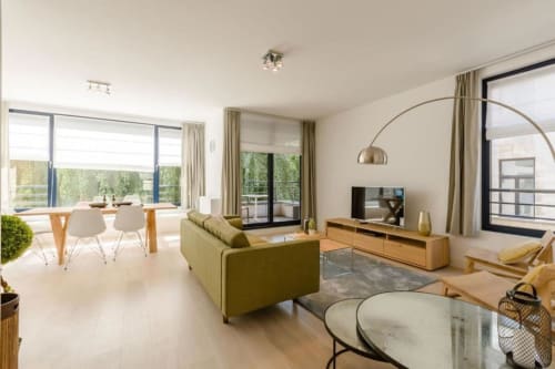 Appartement moderne et élégant au Livorno Bruxelles avec séjour ouvert, canapé vert, mobilier bois et vue sur la ville