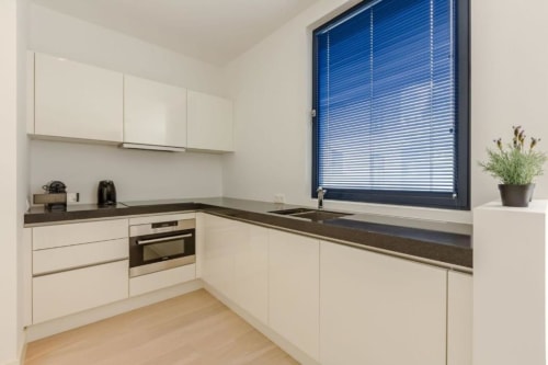Cuisine moderne de l'appartement chic du Livorno à Bruxelles avec armoires crème, plans de travail sombres et acier inoxydable