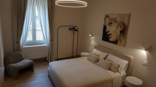 Camera moderna alle Marelia Suites di Vasto con letto queen, poltrona curva, lampada sospesa circolare e vista sulla città