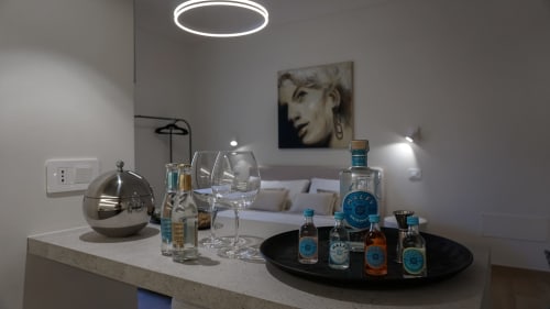Minibar moderno presso Marelia Suites Vasto con esposizione di liquori, bicchieri e illuminazione d'accento