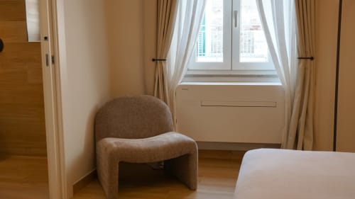 Moderna camera d'albergo presso Marelia Suites a Vasto con poltrona beige curva, pavimenti in legno e vista sulla città