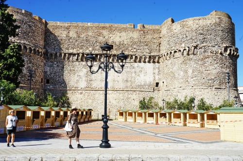 Antica fortezza in pietra con merlature e lampione nero nella piazza di Reggio Calabria