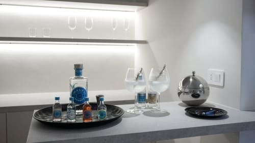 Minibar privato nella suite Marelia con bottiglie di gin, bicchieri con botaniche e cloche di servizio a cupola.