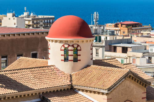 Edificio dalla cupola rossa con finestre ad arco affacciato sul Mare Mediterraneo a Reggio Calabria, Italia
