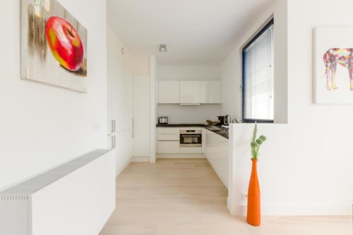 Cuisine moderne dans l'appartement élégant du Livorno à Bruxelles avec mobilier blanc, parquet et art contemporain