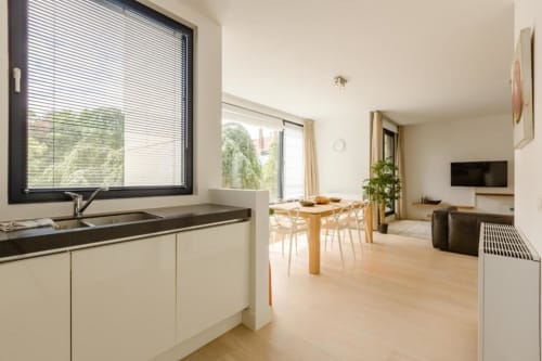 Appartement moderne à Bruxelles avec cuisine ouverte, salle à manger et séjour aux sols en bois clair