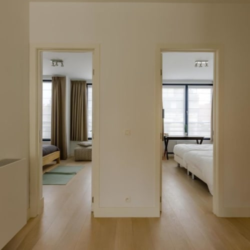 Couloir lumineux dans un appartement bruxellois élégant avec deux chambres et parquet clair