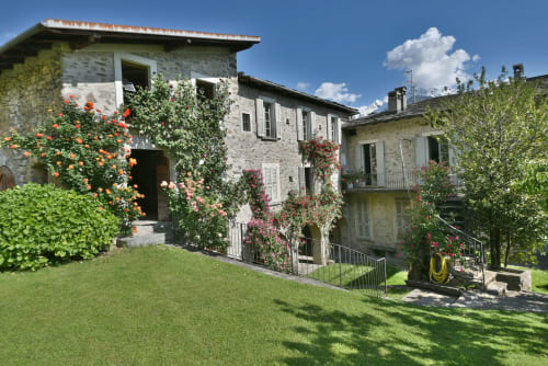 Edifici in pietra con edera e fiori rampicanti nel giardino, Roseto del Drago B&B a Ponte in Valtellina