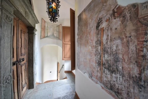 Storico corridoio in pietra a Roseto del Drago, appartamento a Ponte in Valtellina con muri in laterizio a vista e porte in legno